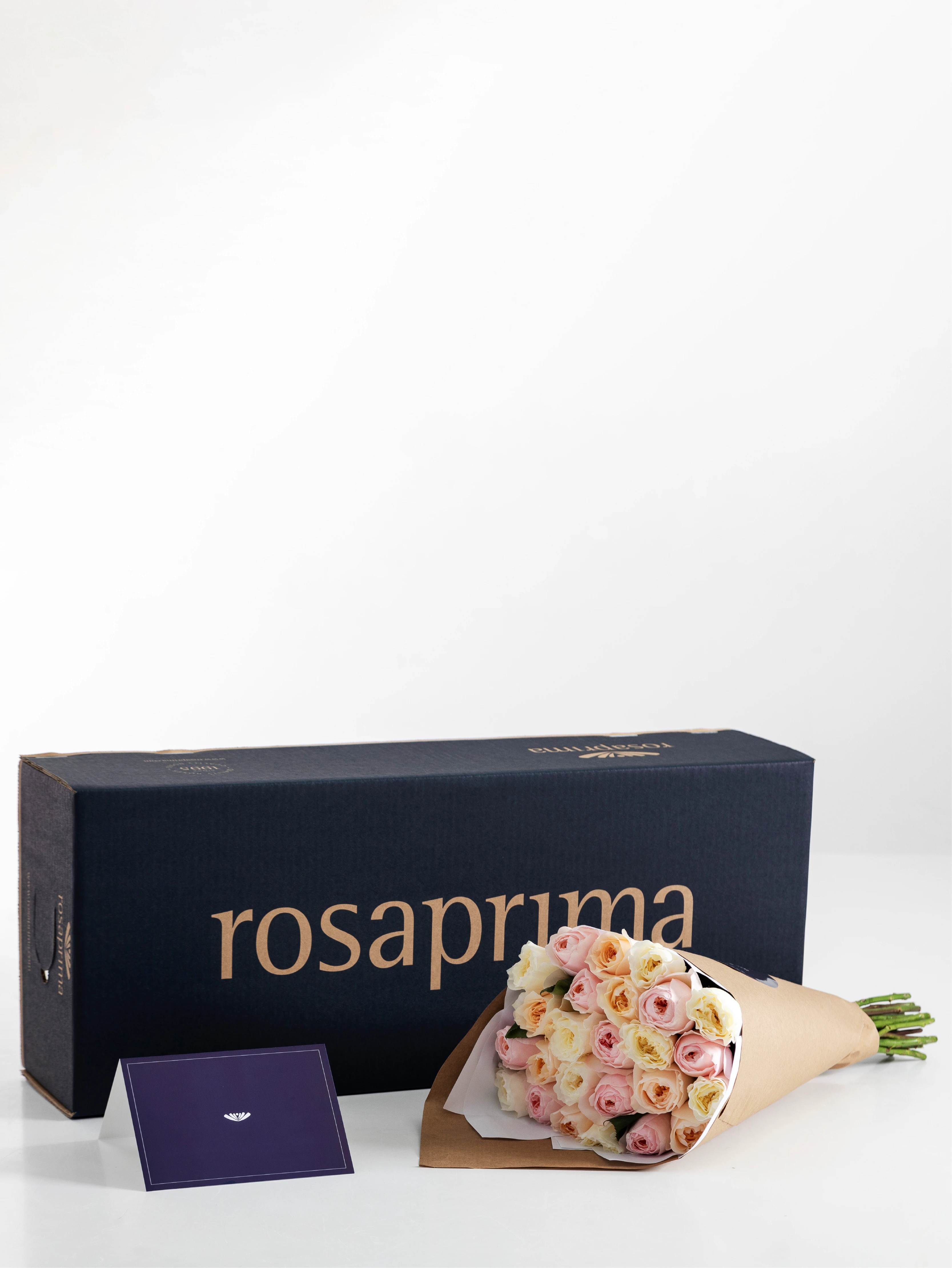 Bouquet of garden roses in a brown paper bag with a Rosaprima box in the background.