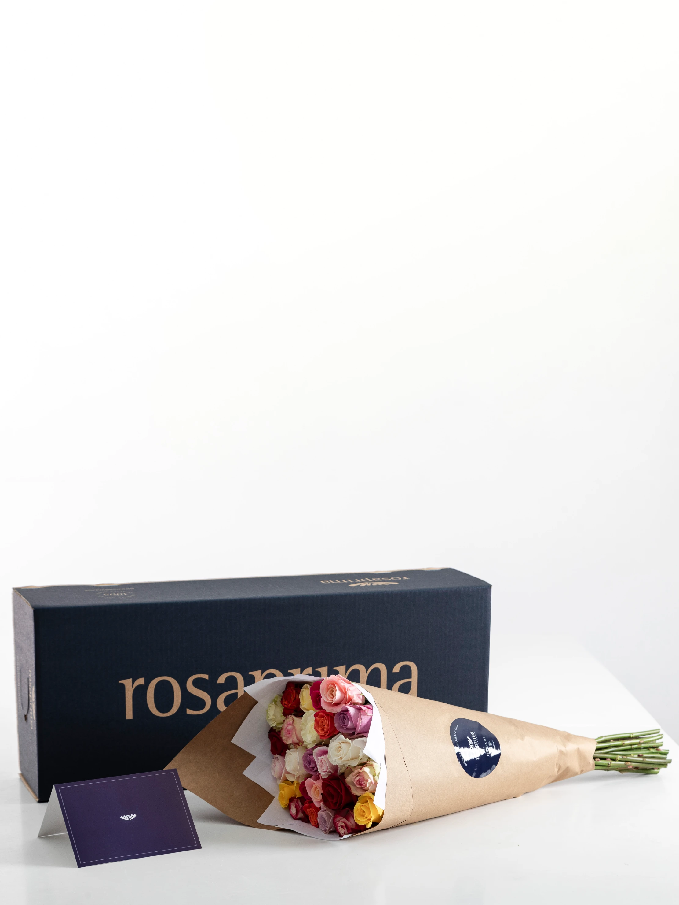 Bouquet of standard roses in a brown paper with a Rosaprima box in the background.